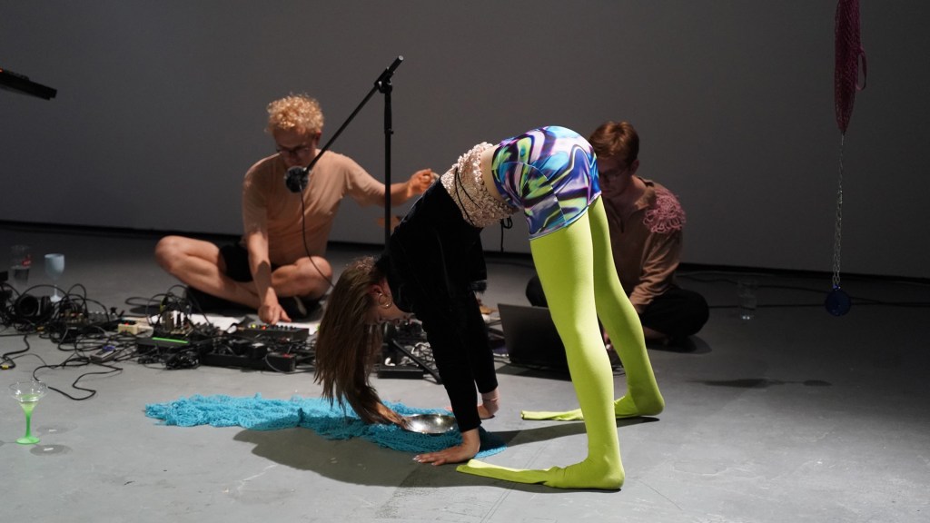 The work imagines a society in which bags are more important than weapons and gathering replaces hunting, proposing a more caring and interdependent vision of humanity. Shifting focus from heroic individuals to collective experience, the performance explores everyday relations, maintenance, and coexistence rather than conflict or conquest. Developed as a performative sound piece combining original texts, movement, and scenography, it reflects on fluid forms of humanity and the cultural “containers” that shape social life, questioning dominant narratives of progress and proposing alternative futures grounded in care and adaptability.